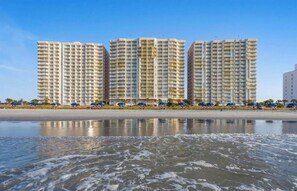 A beachfront hotel with multiple high-rise buildings, a sandy beach, and a calm sea. - Oceanfront Condo with Lazy River (North Myrtle Beach)