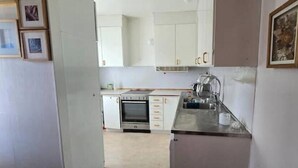 Una cocina con armarios blancos, encimera de acero inoxidable y horno empotrado.