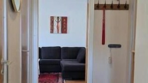 Un pasillo que conduce a una sala de estar con un sofá, un perchero y una puerta.