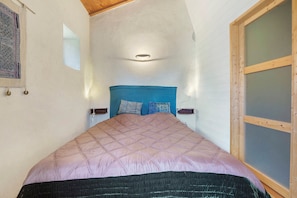 Une piĂšce Ă©troite avec un lit, une petite fenĂȘtre et une porte coulissante Ă cadre en bois.