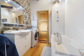 Une salle de bain Ă©quipĂ©e dâun lavabo, dâun lave-linge et dâune baignoire.