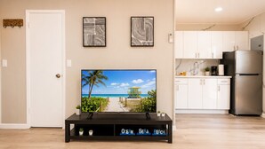 Een woonkamer met een televisie, een houten salontafel en een keuken op de achtergrond.