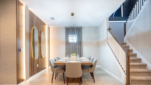 Een moderne eethoek met een houten tafel, stoelen en een kroonluchter.