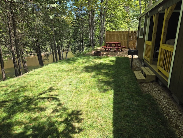 A grassy yard with a wooden deck, picnic table, and a wooden fence.