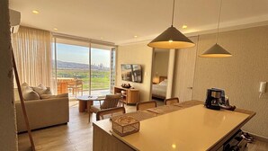 Ein modernes Hotelzimmer mit einer großen Kochinsel, einer Couch, einem Essbereich und Blick auf die Stadt.