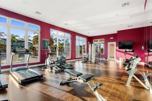 Ein Fitnessstudio mit Laufbändern, Kraftgeräten und einem Fernseher.