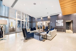A spacious lobby with a modern design, featuring a seating area with sofas and chairs, a large mirror, and a wooden accent wall. - Miami 184 - One Bedroom Apartment, Sleeps 4 (Miami)