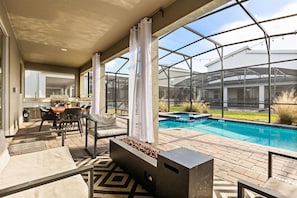 Eine überdachte Terrasse mit Pool, Sitzgelegenheiten im Freien und Grillplatz.