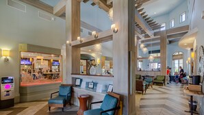 Een lobby met een receptiebalie, een zithoek en uitzicht op het restaurant.
