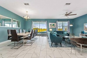 A modern living room with a dining area, large windows, and a ceiling fan. - Last Minute Disney Getaway! Private Pool, Game Room & Themed Bedrooms. Book Now! #173359 (Orlando)