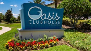 Een bordje voor Oasis Clubhouse bij ChampionsGate, met een aangelegde tuin ervoor.