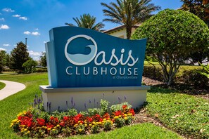 A sign for Oasis Clubhouse at ChampionsGate with a landscaped garden in front. - Last Minute Disney Getaway! Private Pool, Game Room & Themed Bedrooms. Book Now! #173359 (Orlando)