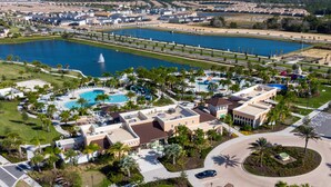 Vista aérea de un resort con una piscina grande, palmeras y un puente sobre el agua.