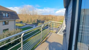 A balcony with a metal railing overlooking a residential area, a clear sky, and a distant view of trees and houses. - Spacious Family Stay in Oostduinkerke (Koksijde)