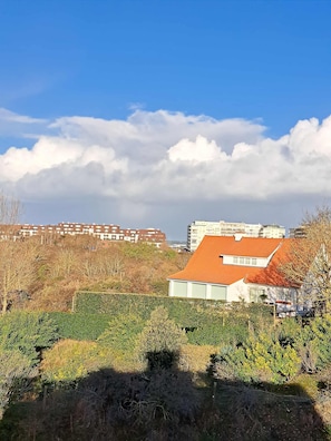 A residential area with a house featuring a red roof, surrounded by greenery and buildings in the background. - Spacious Family Stay in Oostduinkerke (Koksijde)