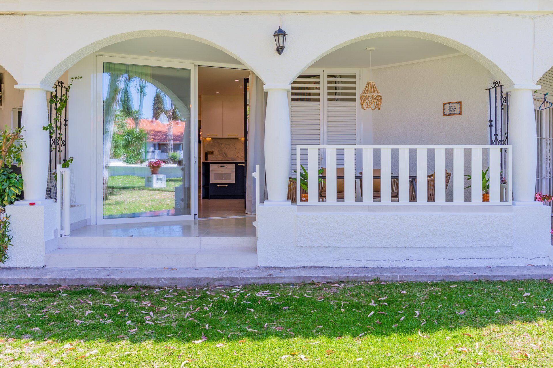 A house with a covered porch, a sliding glass door leading to a kitchen, and a small outdoor seating area.