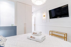 Une chambre d’hôtel moderne équipée d’un lit, d’une télévision et d’une armoire.