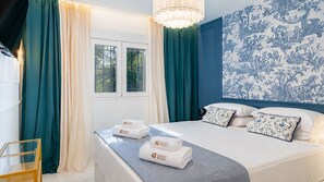 A hotel room with a bed, curtains, a window, and a wall with a blue and white pattern.