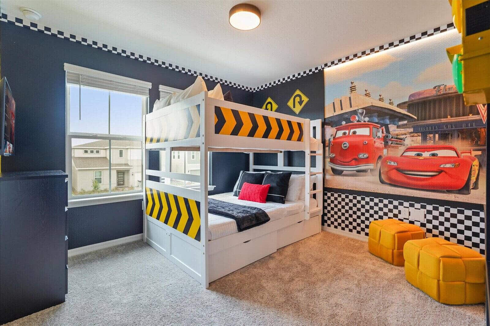 A child's bedroom with bunk beds, a racing car mural, and a window.