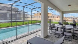 A covered outdoor area with a pool, seating, and a view of the neighborhood. - Last Minute Disney Getaway! Private Pool, Game Room & Themed Bedrooms. Book Now! #173751 (Orlando)