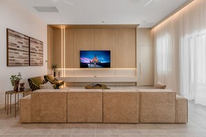 Ein modernes Wohnzimmer mit einer großen, winkelförmigen Couch, einem flachbildfernseher an einer Holzwand und einem minimalistischen Design.