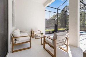 Ein modernes Zimmer mit Glaswand, weißen Möbeln und Blick auf einen Swimmingpool.