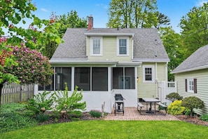 A two-story house with a covered patio, a fenced backyard, and a small garden.