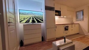 A compact kitchen with a flat-screen TV, wooden cabinets, and a small countertop. - Newly built studio apartment (Gothenburg)