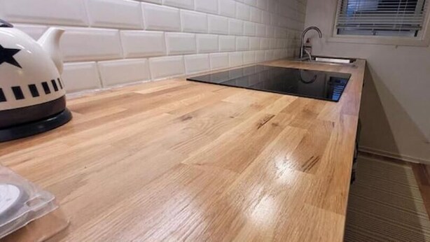 A kitchen with a wooden countertop, a black induction cooktop, and a kettle. - Newly built studio apartment (Gothenburg)
