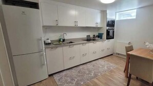 Una cocina compacta con armarios blancos, una mesa de comedor con sillas y una pequeña alfombra.