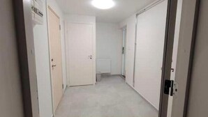 Un pasillo estrecho con puertas blancas, un radiador y una lámpara.