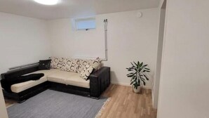 Una sala de estar con un sofá, una mesita, una planta y un ventanal.