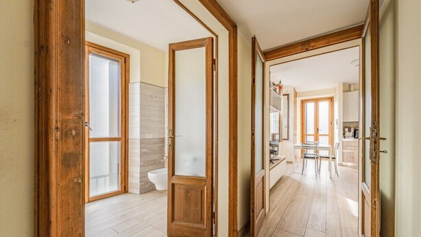 A hallway with wooden doors leading to a bathroom and a kitchen area. - EasyComo - Holiday Home MM (Como)