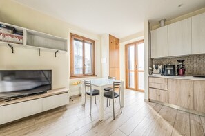 Eine kleine Küche mit Essbereich, Holzboden und einem Fernseher links.