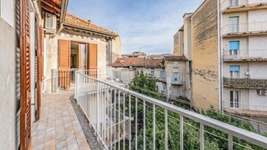 A narrow balcony with a white railing overlooking a row of buildings with traditional architecture and balconies. - EasyComo - Holiday Home MM (Como)