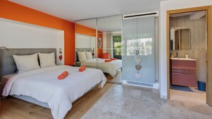 A modern bedroom with a large bed, a separate sleeping area, a bathroom with a mirror and sink, and a sliding glass door to a balcony. - Villa 10 pers with swimming pool, close to the sea (La Croix-Valmer)
