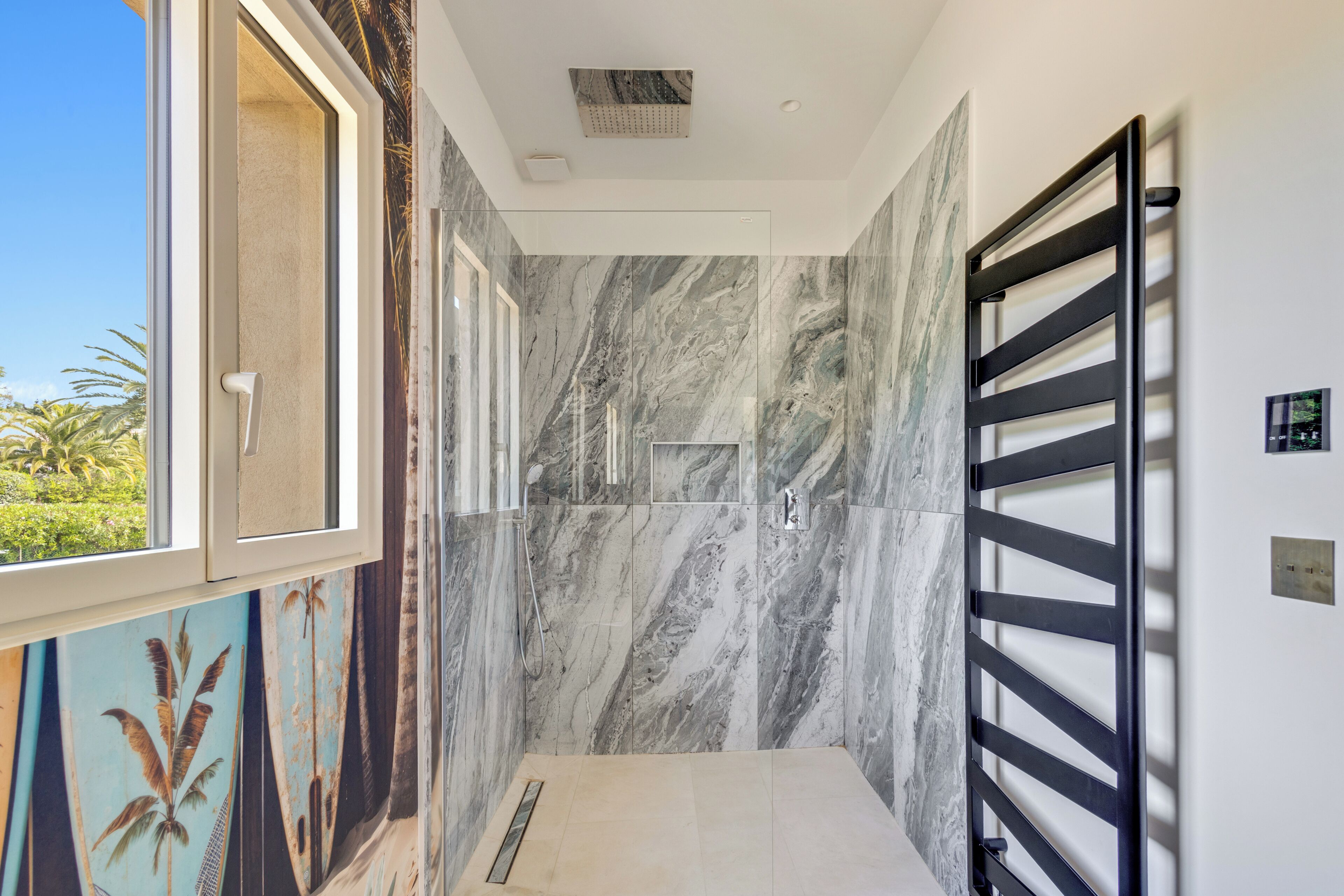 Un bagno moderno con doccia, pareti in marmo e una finestra vista verde.