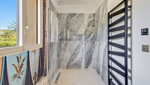 A modern bathroom with a shower, marble walls, and a window with a view of greenery. - Villa 10 pers with swimming pool, close to the sea (La Croix-Valmer)