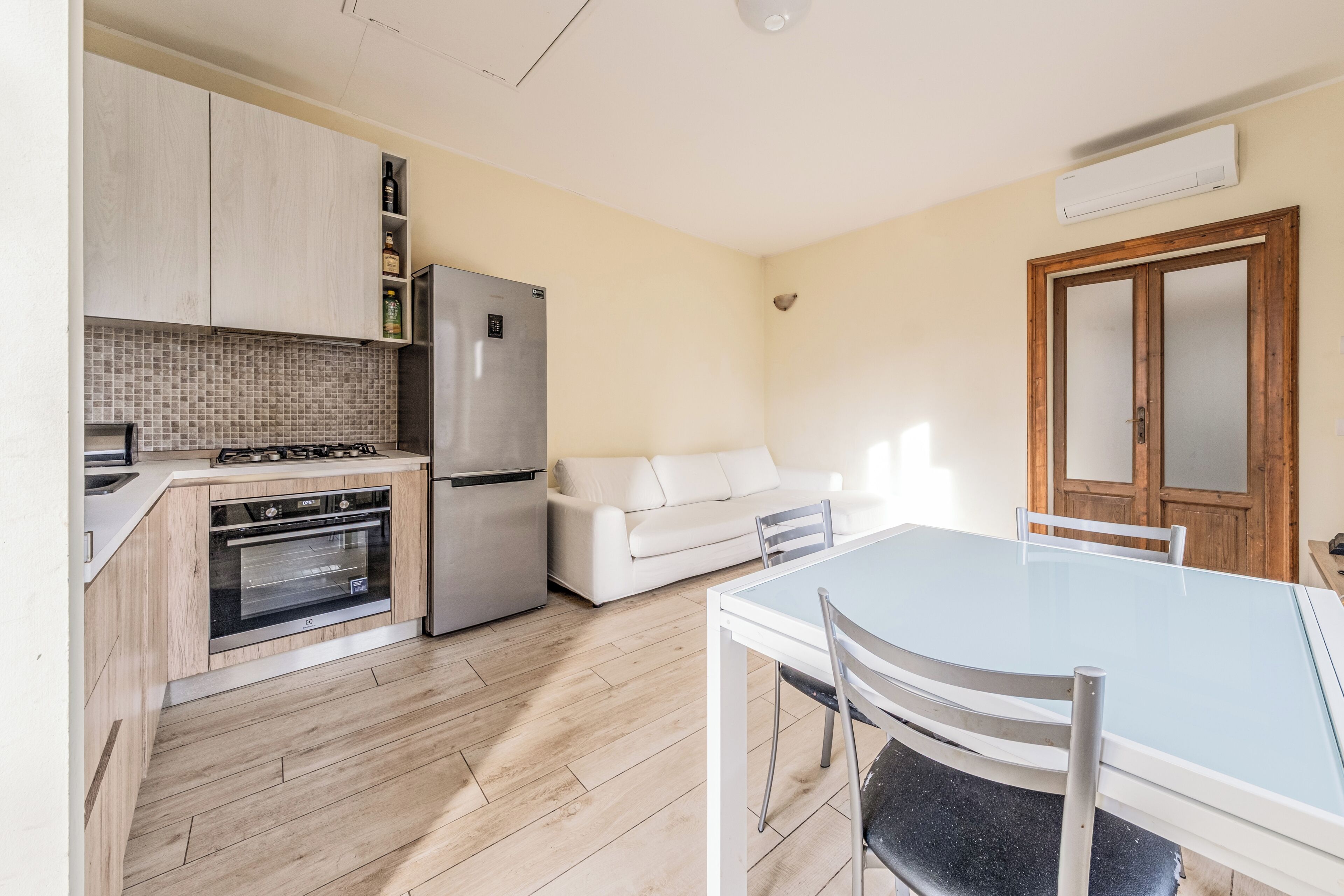 Una cocina con estufa, horno, refrigerador y una mesa de comedor con sillas.