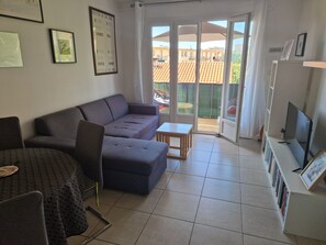 Ein Wohnzimmer mit einer Couch, einem kleinen Tisch, einem Fernseher und einem Bücherregal.