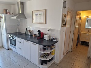 Eine Küche mit Herd, Backofen, Kaffeemaschine, Toaster und einem Regal mit Küchenutensilien.