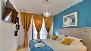 A hotel room with a bed, a television, a painting, and curtains. - Casa Simona - Vue mer incroyable (Ajaccio)