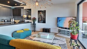 A modern living room with a sofa, coffee table, TV, and a potted plant. - Casa Simona - Vue mer incroyable (Ajaccio)