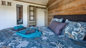 Une chambre à coucher avec un lit, une armoire, un miroir et un mur en bois.