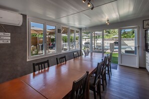 A spacious dining area with a long wooden table and chairs, large windows, and an outdoor patio with umbrellas.