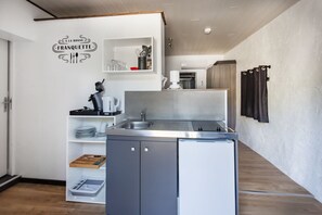 A modern kitchen with a built-in refrigerator, a sink, and a shelf with kitchenware.