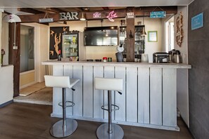 A bar area with two stools, a TV, and a sign that says 'Place de l'Avro'.