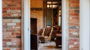A brick interior with a leather armchair and a wooden bench. - The Farmhouse at Nunwell (Brading)