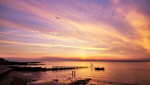 Un atardecer sobre una superficie acuática tranquila con un muelle que se adentra en el agua.