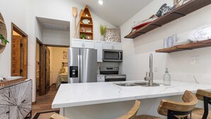 Une cuisine moderne avec des meubles blancs, des appareils en acier inoxydable et un îlot en marbre.